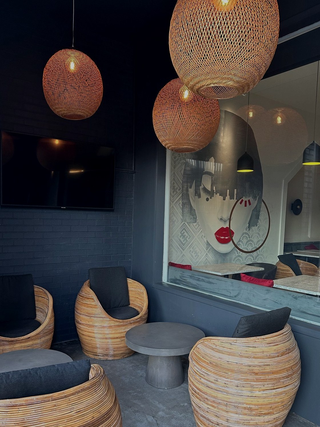 Patio seating with rattan chairs, woven pendant lights, and the dining-room mural through the glass